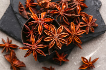 Slate boards with bowl of aromatic star anise on grunge background