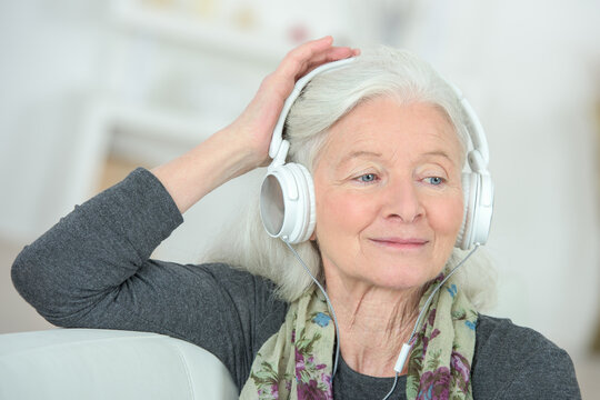 senior woman listening music at home - Powered by Adobe