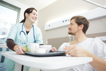 Fototapeta premium young female nurse serving food to male patient