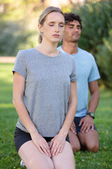 man and woman kneel outdoors in meditattion