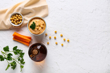 Bowl of tasty hummus with carrot, peas and parsley on white background