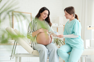 Female doctor with fetal doppler listening to baby's heartbeat in clinic