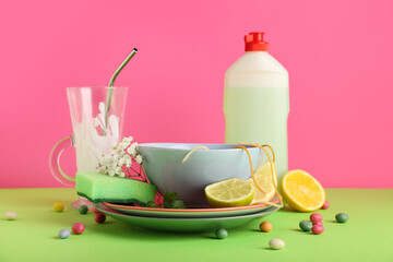 Many dirty dishes with sponge, detergent and leftovers on color background