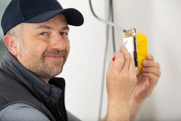 close-up of persons hand installing socket on wall at home