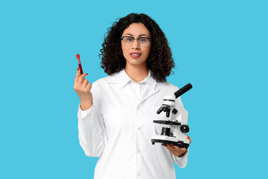 Female African-American scientist with microscope and blood sample on blue background