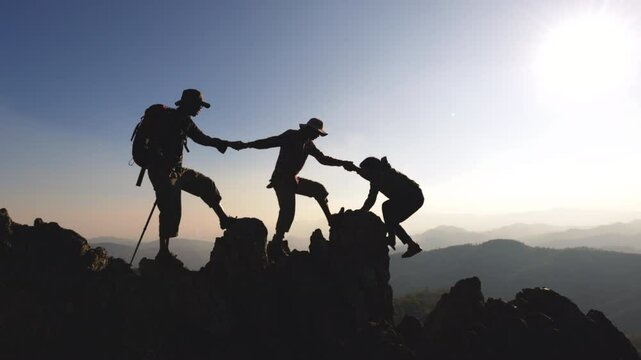 Silhouette of people climbers climb to the top overcoming hardships the path to victory. teamwork  help business travel  concept. group of tourists lends a helping hand climb the cliffs mountains.