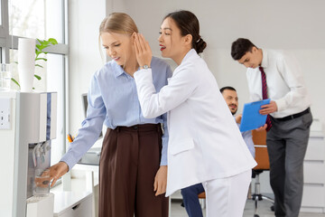 Young business women gossiping near water cooler in office