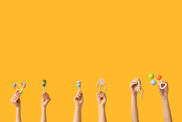 Hands holding baby toys on yellow background
