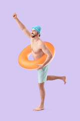 Male swimmer with inflatable ring on lilac background