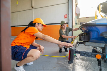 Female mechanics washing watercraft trailer in garage