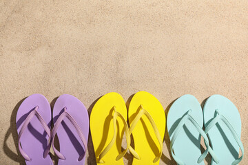 Composition with different stylish flip-flops on sand as background, closeup