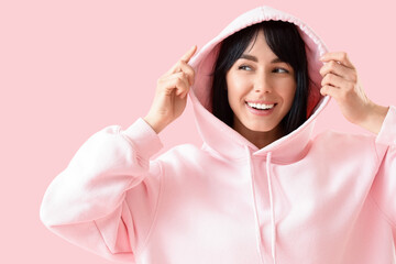 Young woman in hoodie with beautiful smile on pink background, closeup