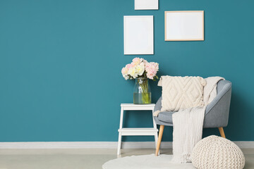 Interior of stylish living room with blue armchair, coffee table and beautiful peonies
