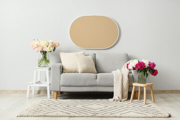 Interior of stylish living room with grey sofa, coffee table and beautiful peonies