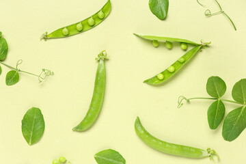 Green pea pods and leaves on color background