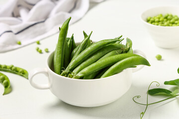 Bowl with green pea pods on white  background, closeup