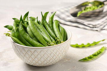 Bowl with green pea pods on grey background, closeup
