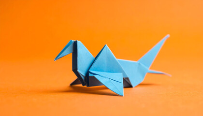A blue origami bird rests against a vibrant orange background, showcasing intricate paper folding artistry and creativity