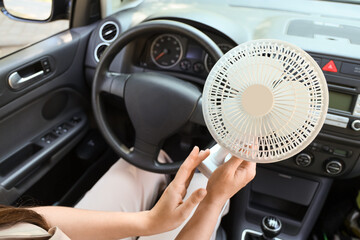 Young woman with mini electric fan in car, closeup