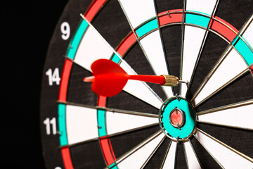 Board with dart on dark background, closeup