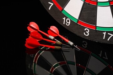Board and darts on dark background, closeup