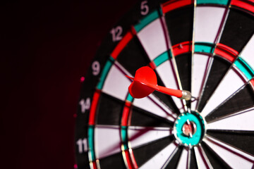 Board with dart on dark background, closeup