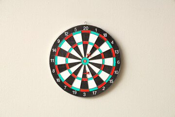 Board with darts hanging on light wall