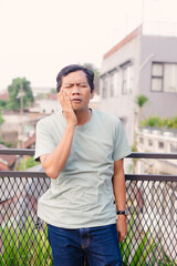 Middle-aged man experiencing discomfort, outdoor setting, emotional expression, facial gesture,
