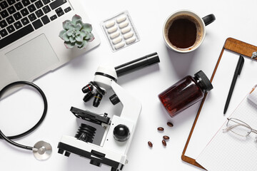 Modern microscope, cup of coffee, pills and laptop on white background