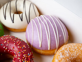 Donuts with different colorful icing designs arranged in a box.
