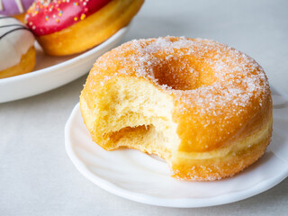 Donuts with sugar sprinkles with bite mark on a white background.