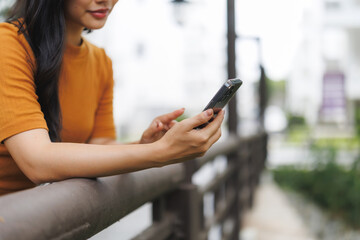 Young woman using smartphone leaning on railing outdoors