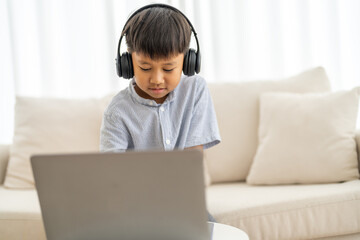 Asian boy using laptop with headphones course online learning, distance education for kids, e-learning at home, child studying digital technology, interactive education platform, remote class tutorial