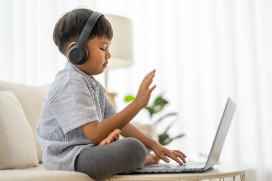Asian boy using laptop with headphones course online learning, distance education for kids, e-learning at home, child studying digital technology, interactive education platform, remote class tutorial