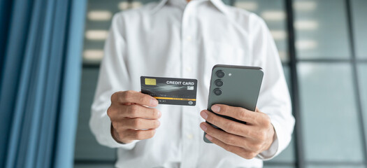 Asian Man paying with credit card on smart phone at office. Male Using Smartphone for Shopping electronic wallet Online 