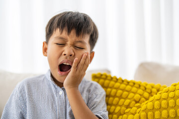 Young child experiencing toothache, tooth decay, childhood dental pain. The child facial...