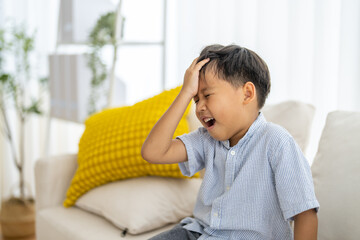 Portrait of sick depressed unhappy child boy touching on head feel suffering head ache pain flu...