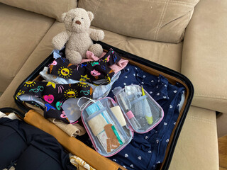 First aid kit packed in a suitcase among children's clothes and a plush teddy bear. A scene...