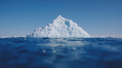 A melting iceberg peak. Global warming. Top of a glacier floating in the ocean and its snowy cover glittering on sun. White ice piece shot from the blue water surface