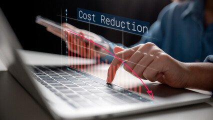 Close-up of a hand using a laptop with a downward cost reduction graph overlay. Concept of expense control, financial efficiency, and cost-saving strategies in business.