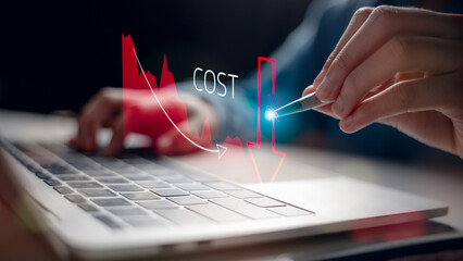 Close-up of a person using a pen on a laptop with a cost reduction graph overlay. Concept of lowering expenses, saving money, and efficient financial planning in business.