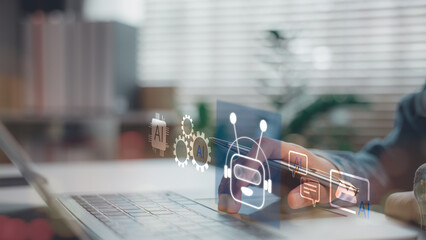 Artificial intelligence for business automation and communication. A person interacts with AI chatbot icons and virtual assistant systems through a digital laptop interface in a modern workspace.
