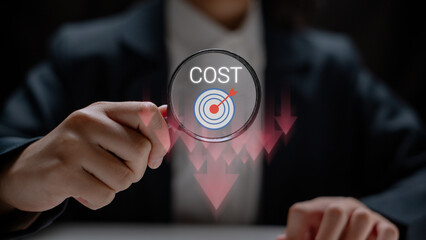 Business person holding a magnifying glass with cost and target icon, symbolizing precise cost reduction, budget control, and financial strategy for business success.