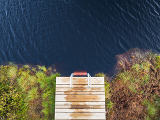 A top-down aerial view of a pier with a swimming ladder in a lake on the hiking trail of Marimetsa...