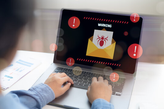 Person working on laptop displaying a warning screen with virus email alert, highlighting the dangers of phishing attacks, malware threats, cyber risks, and the importance of email security.