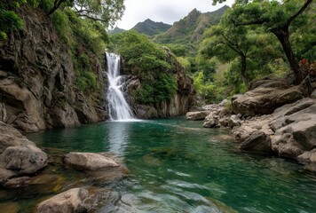 Serene Waterfall Cascading into Crystal Clear Pool Surrounded by Lush Greenery and Rocky Terrain in Majestic Mountain Landscape