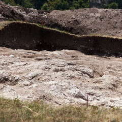 Archaeological excavation site with exposed soil layers and chalky terrain