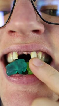 Vertical screen candy damage close-up of decayed and missing teeth while chewing gummy bears emphasizes dental problems linked to excessive sugar consumption and poor oral hygiene