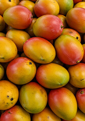 a pile of ripe mangos filling the entire frame, smooth skins with yellow
