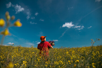 Trendy woman with stylish hat feeling free in the field with flowers